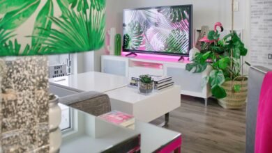 A stylish living room featuring tropical-themed decor, plants, and a modern TV setup.
