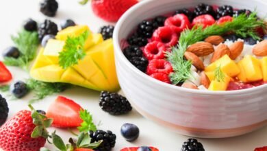 A vibrant bowl filled with fresh berries, mango, almonds, and herbs, perfect for a healthy snack or breakfast.