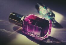 Artistic close-up of a pink nail polish bottle with reflective light and vivid colors.