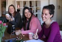 Three women enjoying a collaborative and friendly workplace meeting indoors.