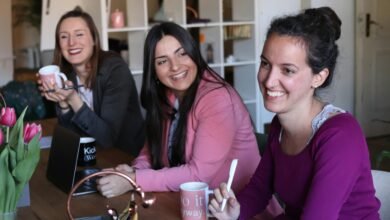 Three women enjoying a collaborative and friendly workplace meeting indoors.